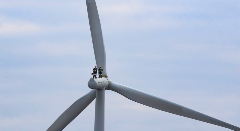 Two workers stood atop a wind turbine on its engine
